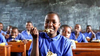 Foto: WFP/Aristide Gatera Una estudiante come su almuerzo escolar en su pupitre.